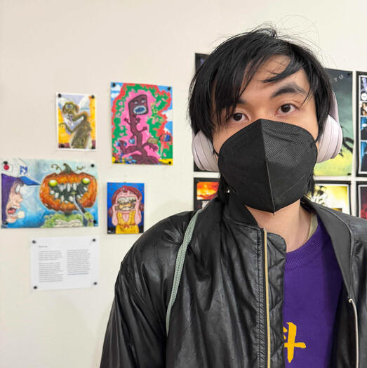 Posing in front of his art in “Next Generation of Comics Artists in the Pacific Northwest” showcase, Northwest Museum of Cartoon Arts (Portland, OR) November 2025 opening preview
